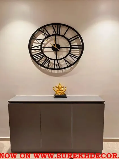 This simple and glamorous vintage wall clock features classic Roman numerals on a large, open metal frame. Its timeless design and antique finish make it a versatile choice for adding a touch of elegance above a console or in a dining area.