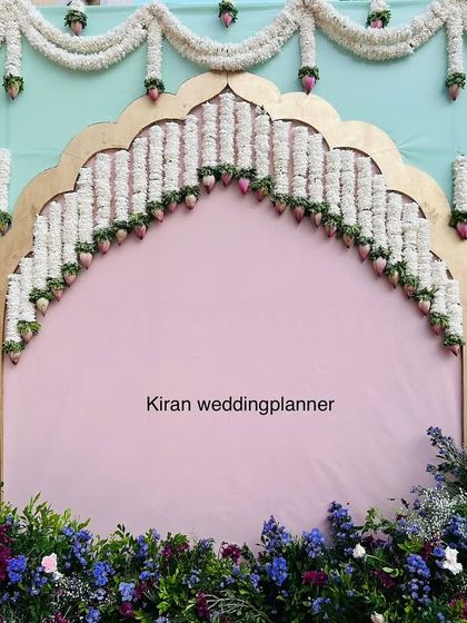 A simple yet chic pastel-themed backdrop. The combination of a mint green wall, a pink arch lined with jasmine, and a base of colorful flowers is perfect for daytime events.