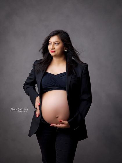 A confident and stylish portrait. The open blazer look is a modern and fashionable way to showcase the baby bump in a powerful and beautiful way.