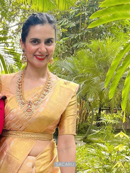 A smiling portrait of our client Madhuri, showcasing the elegant neckline of her custom gold blouse and her traditional jewelry.