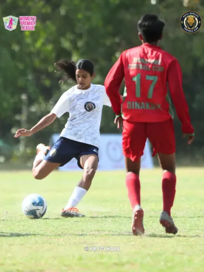 A player lines up a powerful kick, demonstrating technique and focus as she looks to move the ball upfield against an opponent.