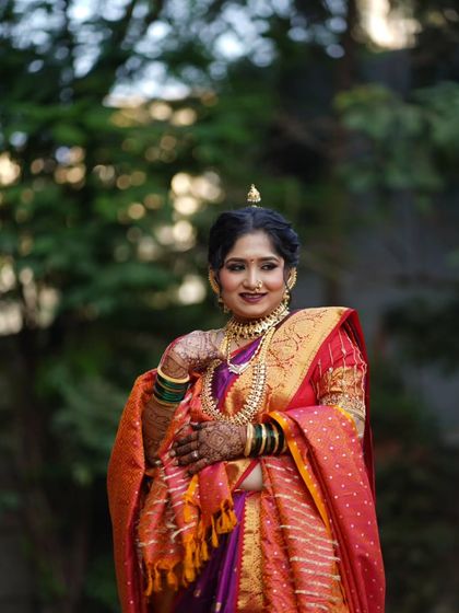 A beautiful portrait highlighting the rich colors of the Maharashtrian wedding attire. The makeup features a deep lip color and defined eyes to match the grandeur.