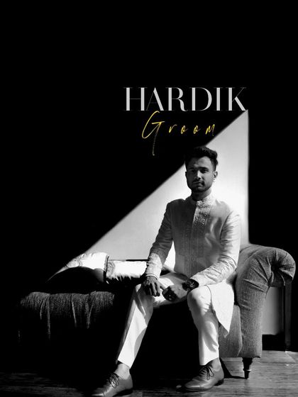 A dramatic black and white portrait of the groom, seated, with a single beam of light creating a powerful, moody effect.