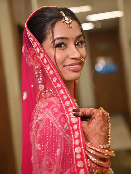 This bride's side profile shows off the clean lines of her makeup and the beautiful detailing of her pink bridal outfit. A look that is both modern and traditional.
