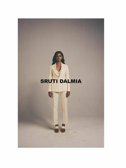 A minimalist look from the Sruti Dalmia campaign, featuring a clean, tailored off-white suit. The studio styling is stark and direct, focusing entirely on the garment's sharp silhouette and modern aesthetic.
