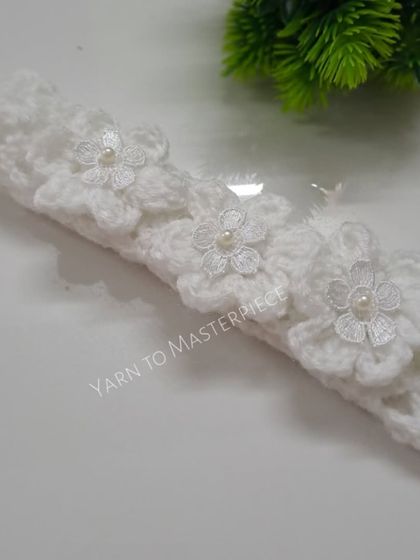 This delicate white floral headband is perfect for a baptism or other formal event. It's made with soft cotton yarn and features three flowers, each with a tiny pearl in the center.