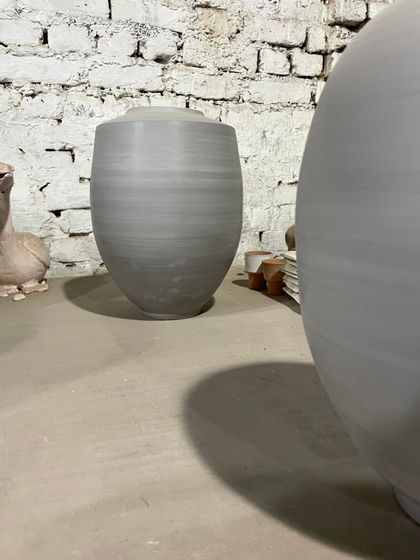 A quiet corner of the studio, showing the simple, elegant forms of my unfired vases and jars. In the background, a clay bird sculpture is also drying.