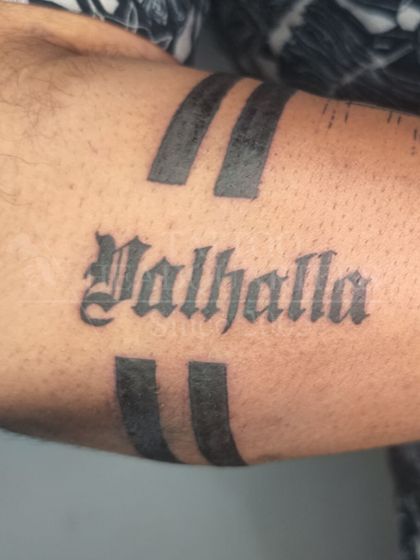 The word "Valhalla" in a classic blackletter (gothic) font, framed by two bold armband stripes.