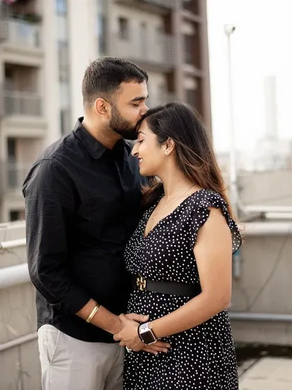 An urban rooftop setting provides a modern backdrop for a maternity shoot. This tender moment, with a gentle kiss on the forehead, feels both intimate and stylish.