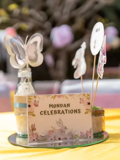 A table centerpiece for the Mundan celebration, featuring butterfly and bunny toppers and a custom sign. The theme was consistently applied to every detail of the event.