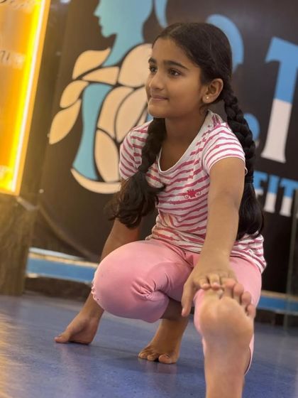 A quiet moment of focus during a dance session. This student is practicing a stretch, highlighting the importance of flexibility and proper form that we teach in every class.