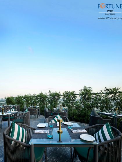 The clear blue sky provides a stunning daytime contrast to the green foliage and modern furniture of our rooftop restaurant.