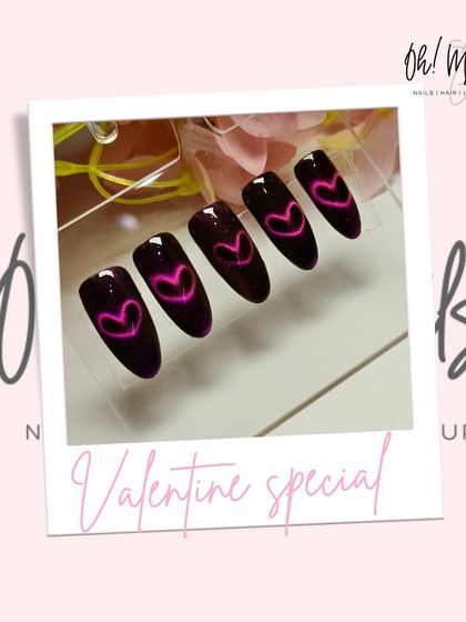 A Valentine's glow-up. These unique nails feature a dark base with a vibrant pink cat eye effect shaped into a heart, creating a glowing, magnetic design.