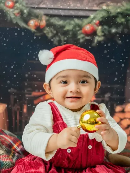A beautiful close-up portrait, highlighting her bright eyes and happy smile as she holds a Christmas bauble.