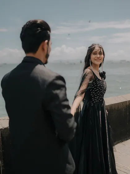 The classic "follow me to" pose, but with a genuine smile and connection. This shot, with the Mumbai sea in the background, is both playful and romantic.
