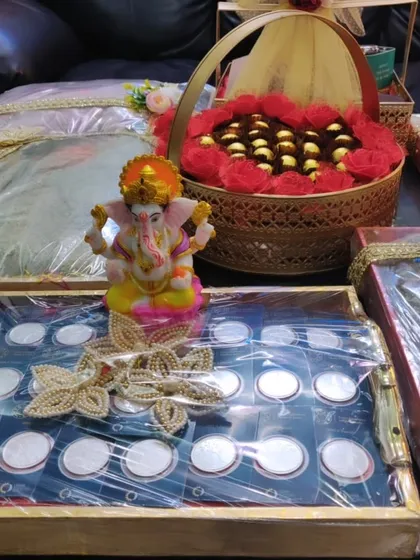 Here is a complete sagan and trousseau display I put together. It includes a tray of silver coins with a Ganesha idol, a basket of chocolates, and beautifully wrapped outfits, creating a cohesive and impressive presentation for the ceremony.