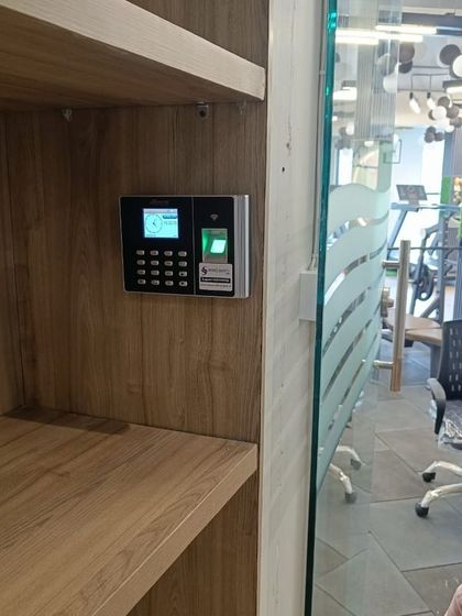 Here's a biometric reader installed inside a wooden shelving unit at a gym. This placement keeps the device accessible but integrated into the reception area's design.