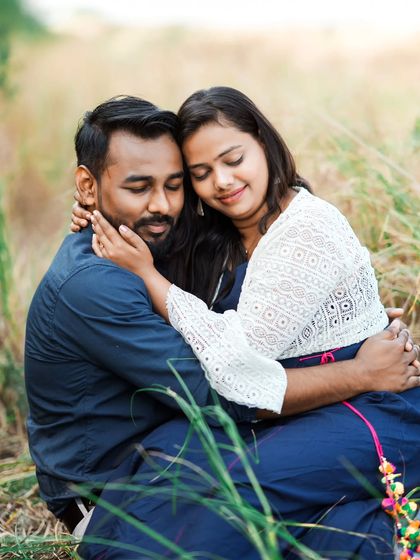 A tender embrace in a field of tall grass. The natural setting and soft light create a feeling of warmth and intimacy.
