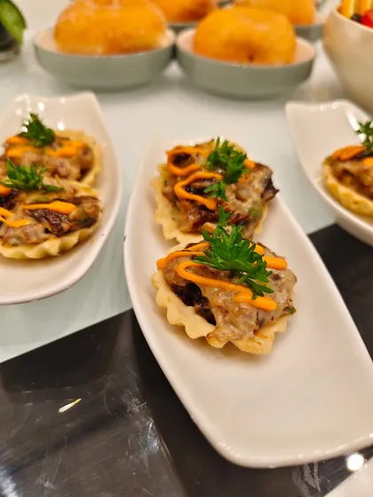 Snack time goes gourmet! Each crispy tartlet is topped with a savory medley, melty cheese, a drizzle of zesty sauce, and a touch of fresh parsley.