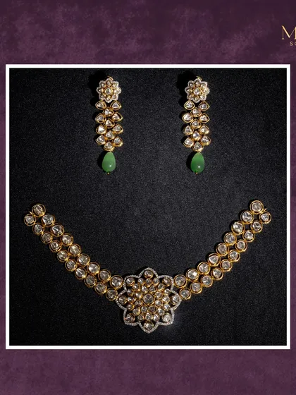 This floral-inspired Polki necklace set is a statement of sophistication and grace. The matching earrings with green drops add a subtle touch of color to the warm glow of the uncut diamonds.