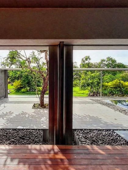 This courtyard design incorporates a small pool and a single tree, creating a serene, minimalist landscape. The space serves as a visual focal point and a natural cooling element for the building.