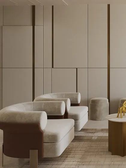 A detail of the sculptural seating, where clean, linear wall panels are balanced by the soft curves of the armchairs. Touches of gold and deep brown ground the creamy palette with warmth and richness.