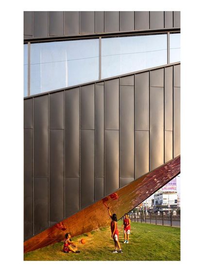 Children play on the landscaped berm of the "Figured Ground" sports arena. The building's exterior is designed to be an active part of the campus, a place for informal gathering and play.