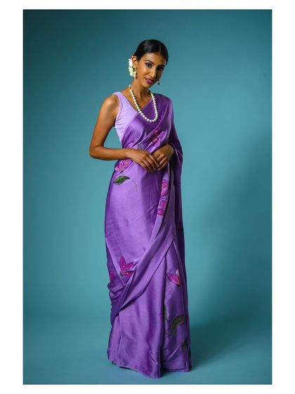 A full-body shot that captures the grace of this purple saree. The model's pose and the clean background ensure the product remains the central focus.
