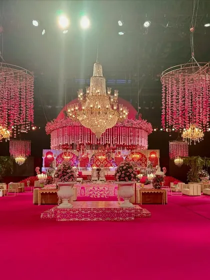 A wide view of the circular pink mandap, showing its central placement in the hall and the surrounding guest tables, all unified by the vibrant pink color scheme.