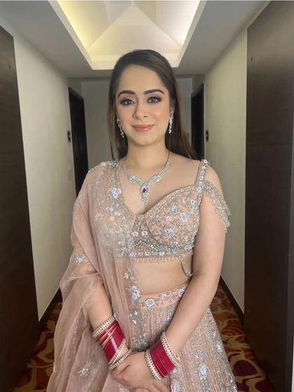 A smiling bride with her hair in soft, open waves, complementing her pastel lehenga. This is a fresh and modern look for any daytime wedding event.