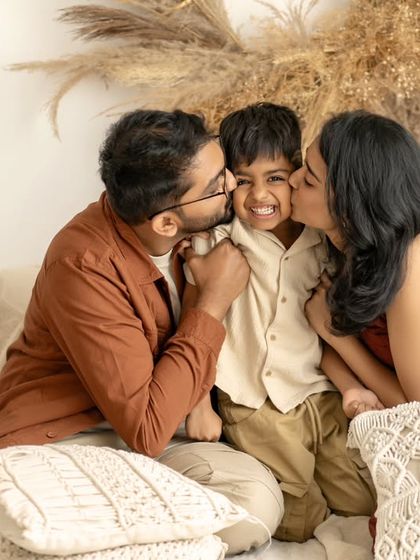 A shower of kisses for one very loved little boy. This photo perfectly captures the affection and warmth of a family, a beautiful memory of a moment filled with love.