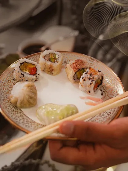 A guest's plate featuring a selection of our Asian specialties, including sushi and delicate dim sum, showcasing the fine culinary artistry our chefs bring to each dish.