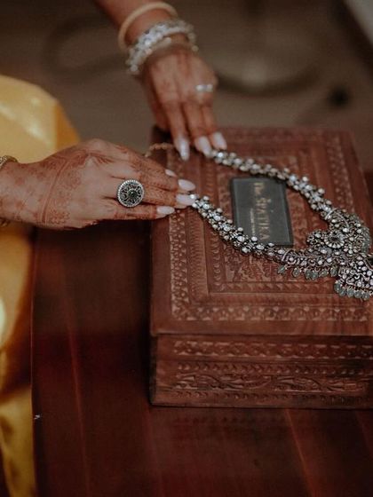 A detailed shot of the bride's hands with her engagement ring, resting on an ornate wooden jewelry box.