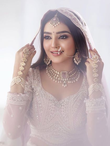 A beautiful portrait of the bride adjusting her veil. The soft lighting creates a dreamy and romantic atmosphere.