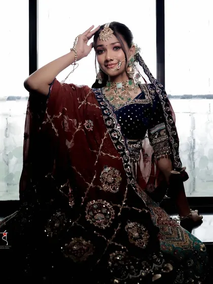A striking pose against a window, this bride looks absolutely regal. The lighting highlights the rich textures of her velvet lehenga and the sparkle of her jewelry.