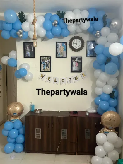 A simple and sweet "Welcome Home" decoration for a baby. The balloon arch frames the family photos on the wall, making it a very personal and heartwarming setup.
