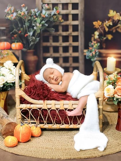 A wide shot of the rustic autumn-themed setup. This shows the full context of the scene, with the tiny baby being the peaceful center of a beautifully arranged, cozy little world.