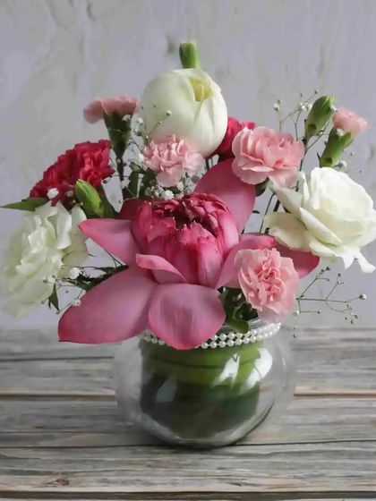 A lovely vase arrangement of pink and white carnations with a lotus bud. It's a thoughtful and ready-to-display gift for any occasion.