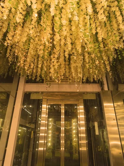 A stunning floral installation with fairy lights hanging from the ceiling above the venue's glass elevator, making for a grand entrance.