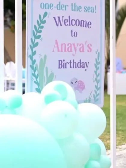 A close-up of the welcome sign for Anaya's 'one-der the sea' birthday, with soft mint green balloons adding to the aquatic feel.