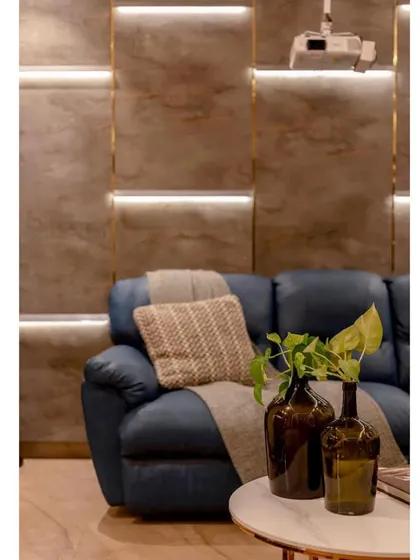 A close-up of the textured, backlit wall paneling behind the blue sofa. This detail adds depth and a high-end, custom feel to the entertainment space.
