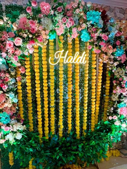 Why stick to just yellow? This multi-colored Haldi decoration combines traditional marigolds with a lush arch of pink, blue, and white flowers for a unique and vibrant look.