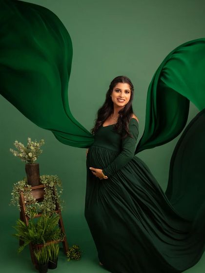 A vision in green. The flowing fabric of the dark green gown creates a sense of movement and drama, beautifully contrasting with the mother's serene expression.