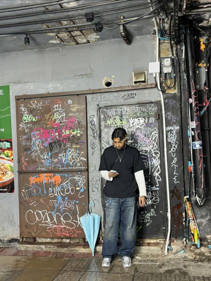A candid moment checking my phone in front of a graffiti-covered wall. The streets are always a source of inspiration.