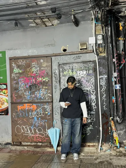 A candid moment checking my phone in front of a graffiti-covered wall. The streets are always a source of inspiration.