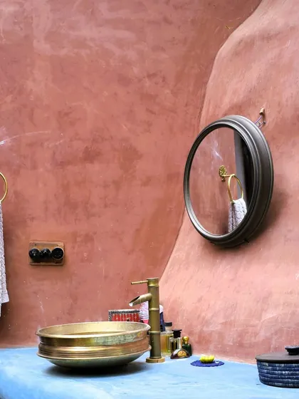 We love using natural, breathable materials like this mud and lime plaster. It not only gives the wall a beautiful, earthy texture but also helps regulate the temperature, keeping the home cool naturally. The brass sink and blue countertop add a touch of modern craft.
