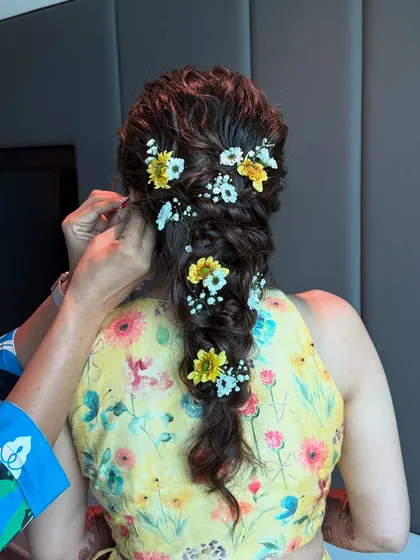 A close-up of our hairstylist creating a beautiful messy braid for a Haldi bride, weaving in fresh flowers for a touch of sunshine.