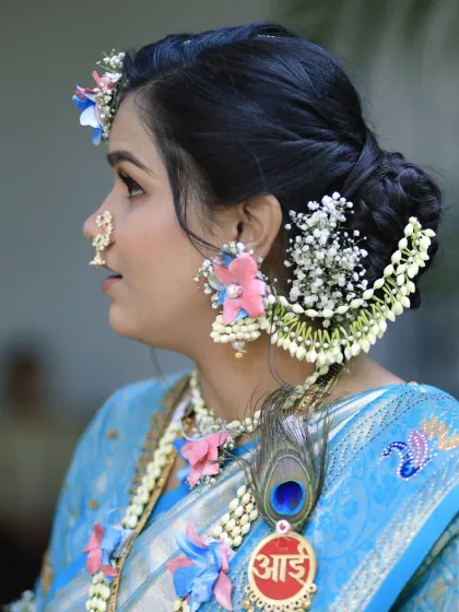 It's all in the details. This photo showcases a traditional Maharashtrian hairstyle, a beautifully crafted bun or 'khopa' adorned with fresh baby's breath and jasmine, perfect for a baby shower look. Notice the custom 'आई' (Mother) brooch, a special touch for the occasion.