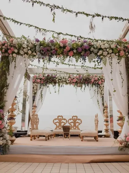 A rustic yet romantic mandap setup at the Intercontinental Marine Drive. The combination of a wooden frame, lush greenery, and pastel florals creates an intimate and beautiful atmosphere with an open sky view.