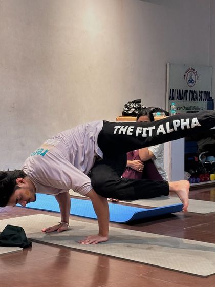 A student holds Astavakrasana (Eight-Angle Pose), a complex arm balance that strengthens the entire body.